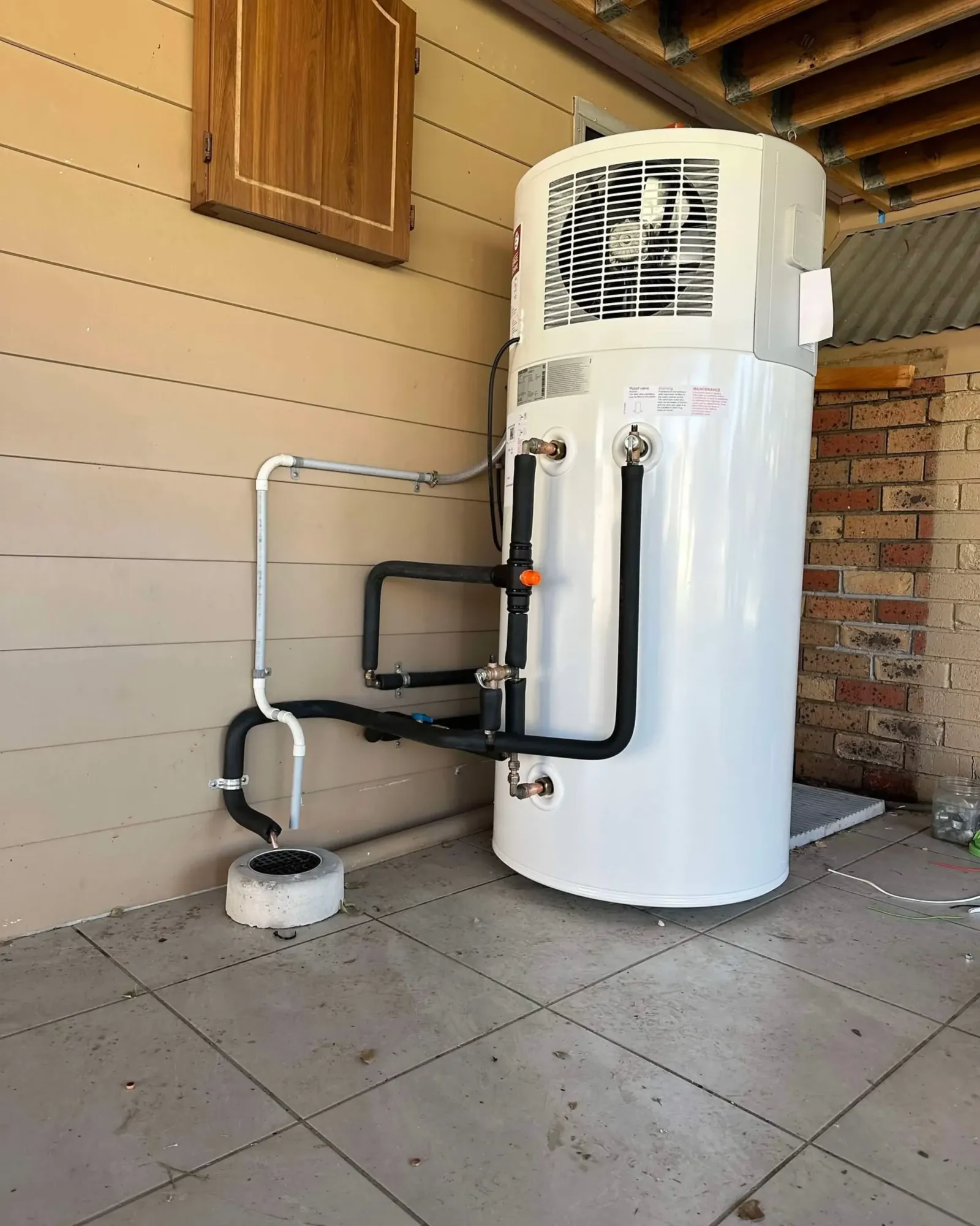 Heat pump hot water system installed on a tiled patio