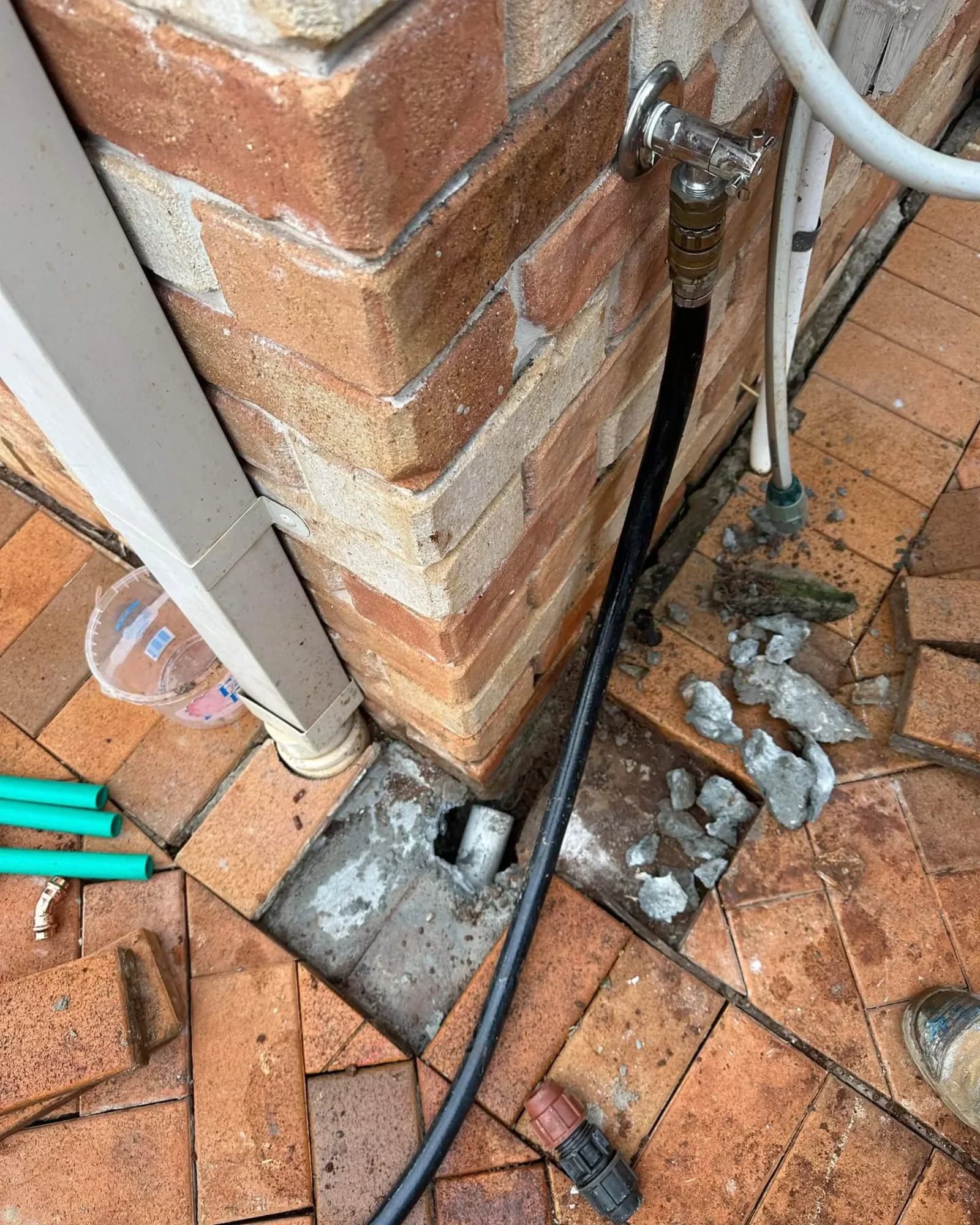 Outdoor tap and hose connected beside a brick wall