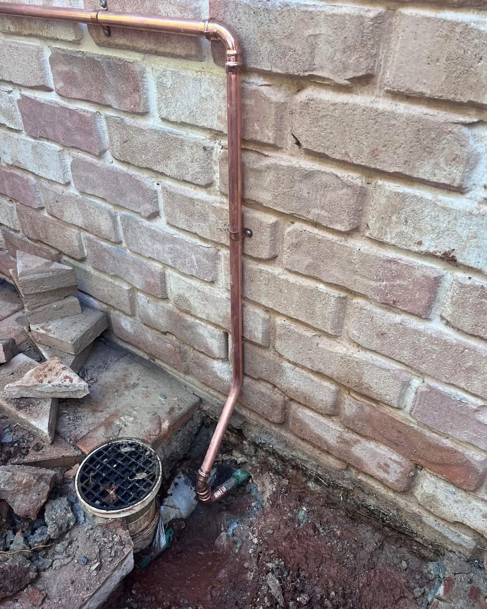 Overflow relief gully grate beside a brick wall