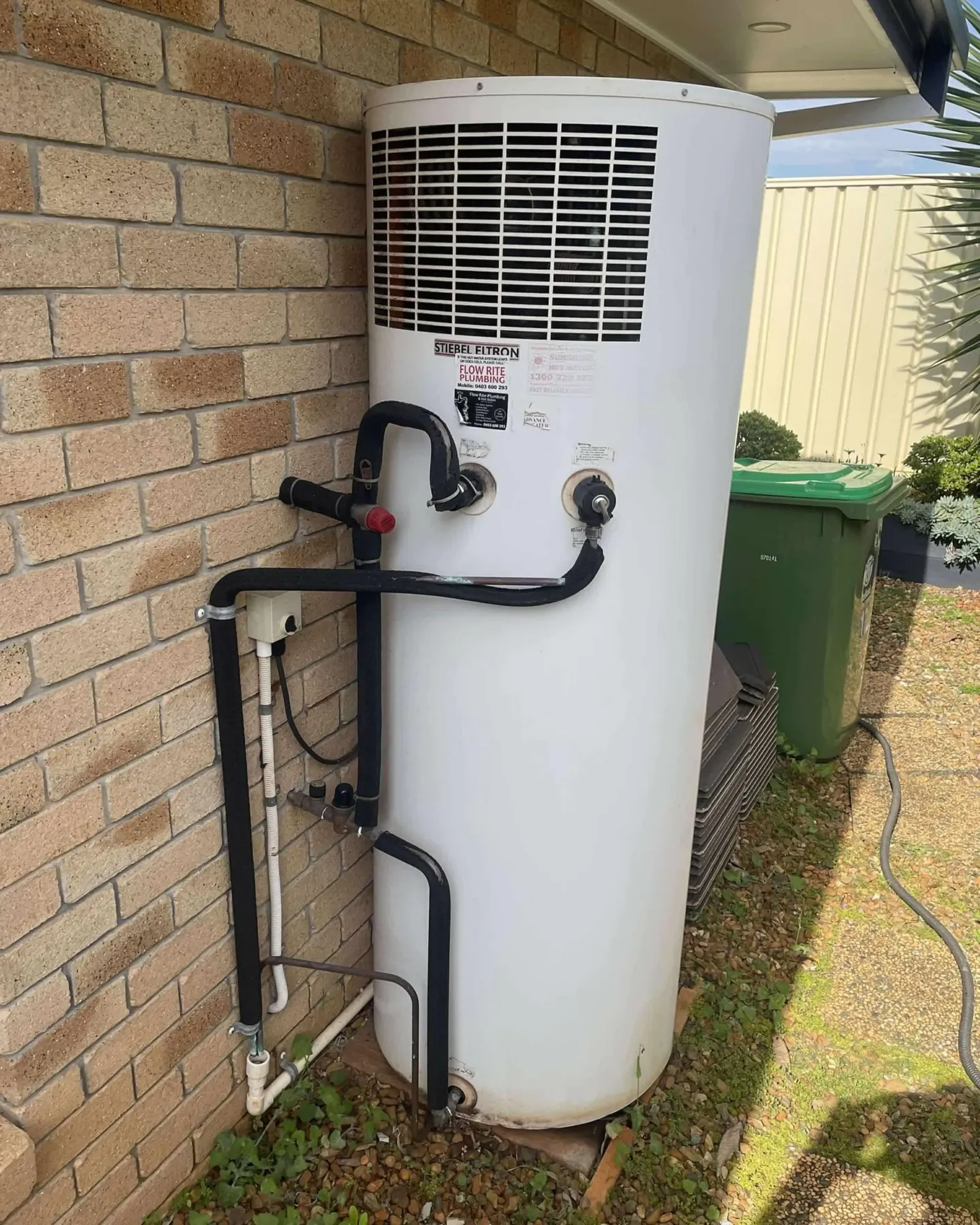 Heat pump hot water system installed against a brick wall