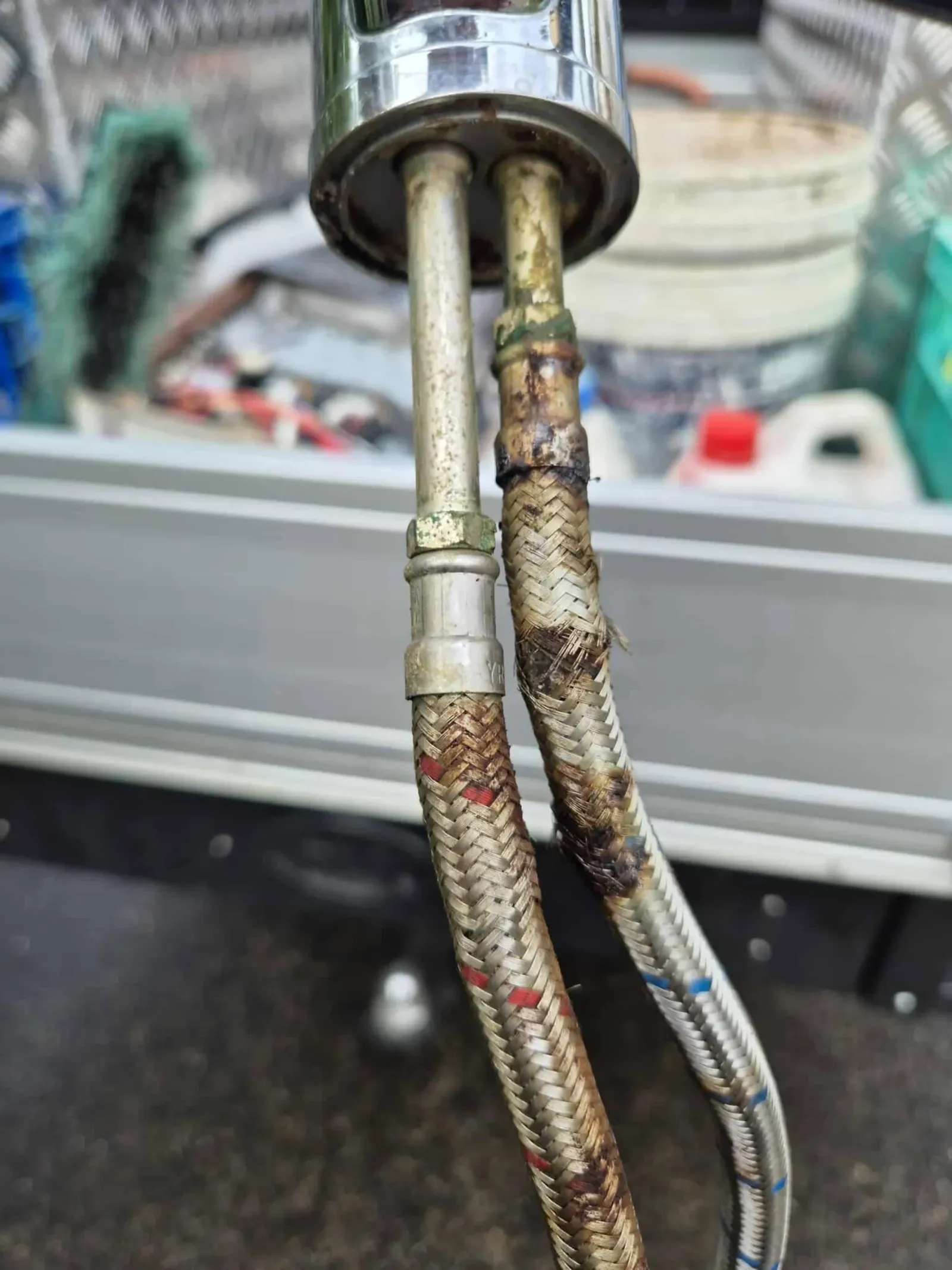 Corroded braided tap hoses under a kitchen sink