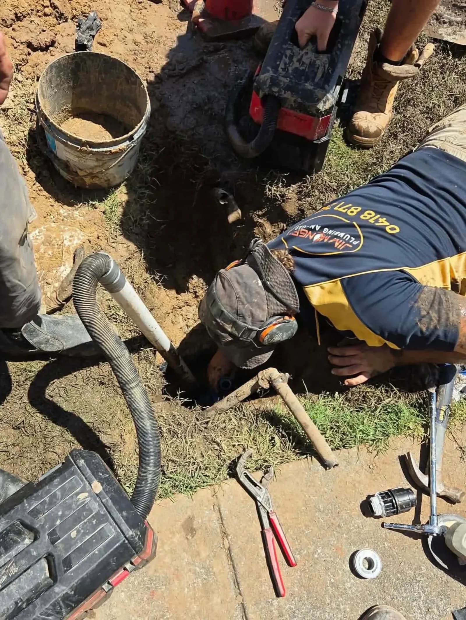 Plumber working in a hole to repair a pipe