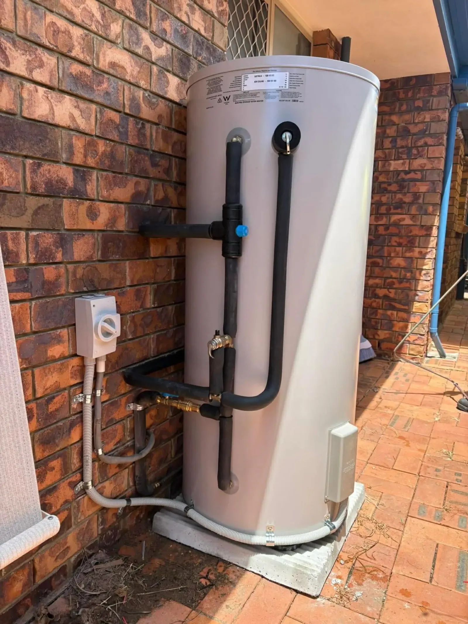Electric hot water system installed in a brick corner