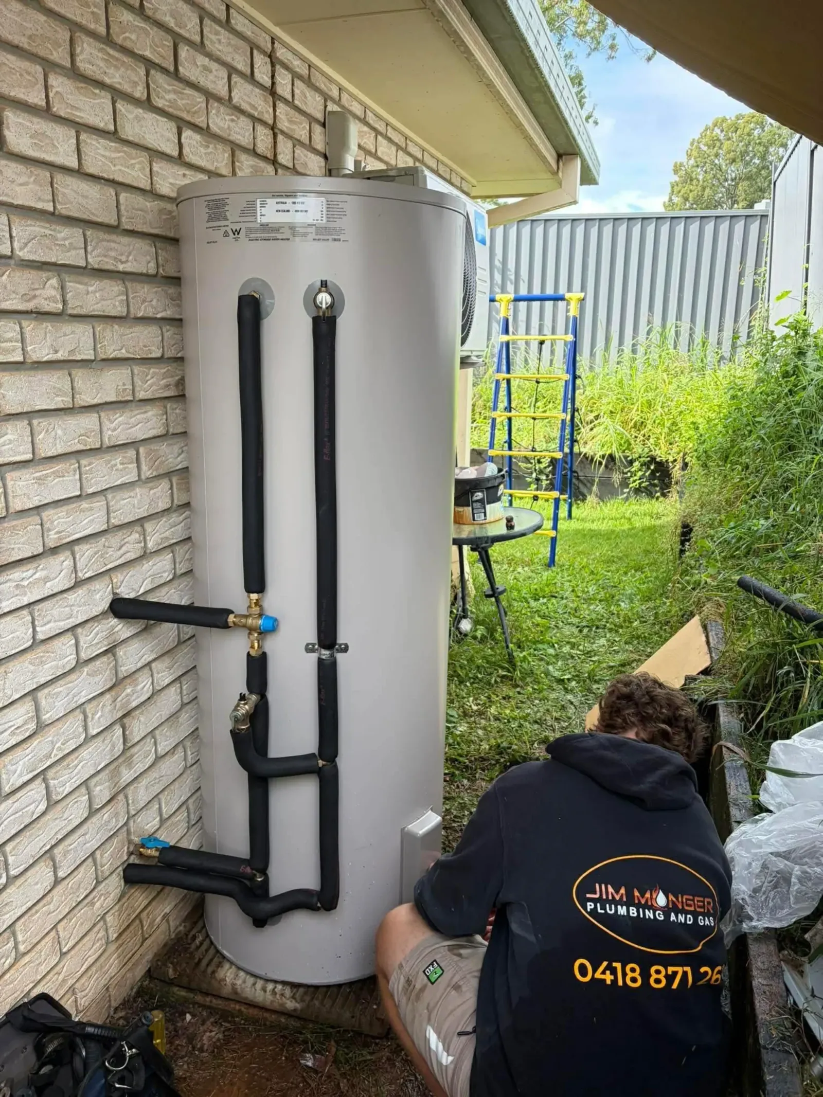 Plumber installing an electric hot water system
