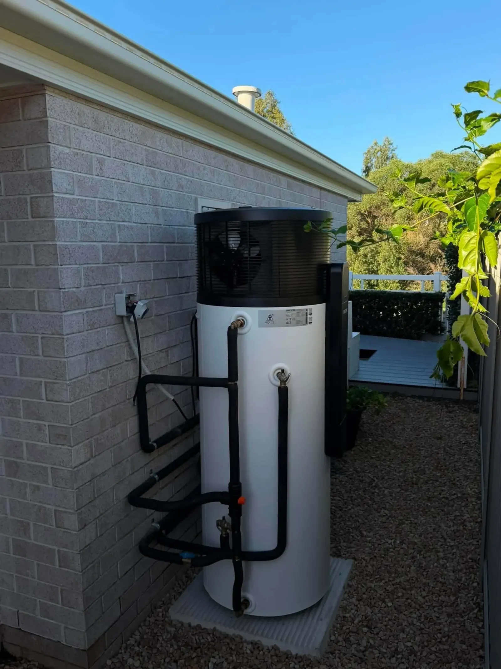 Heat pump hot water unit installed along a side path