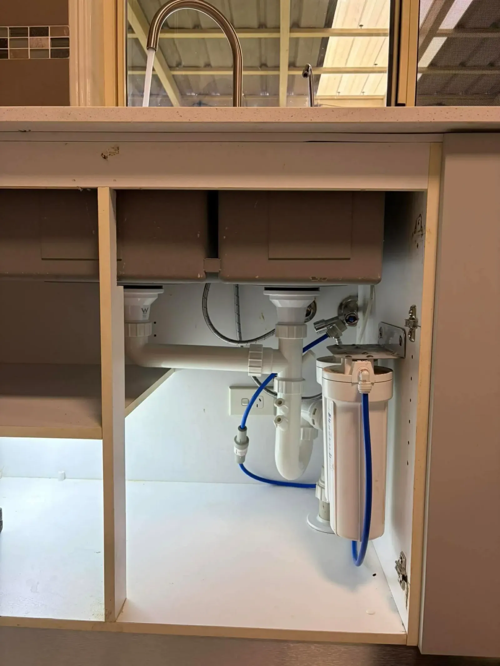Water filter and waste pipes serviced under a kitchen sink