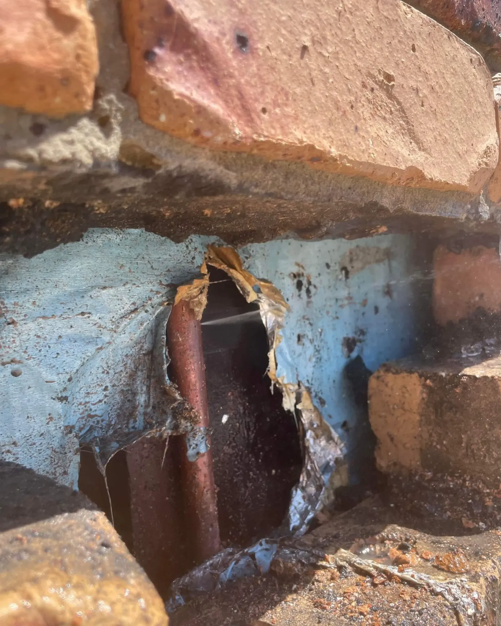 Burst water pipe exposed inside a brick wall