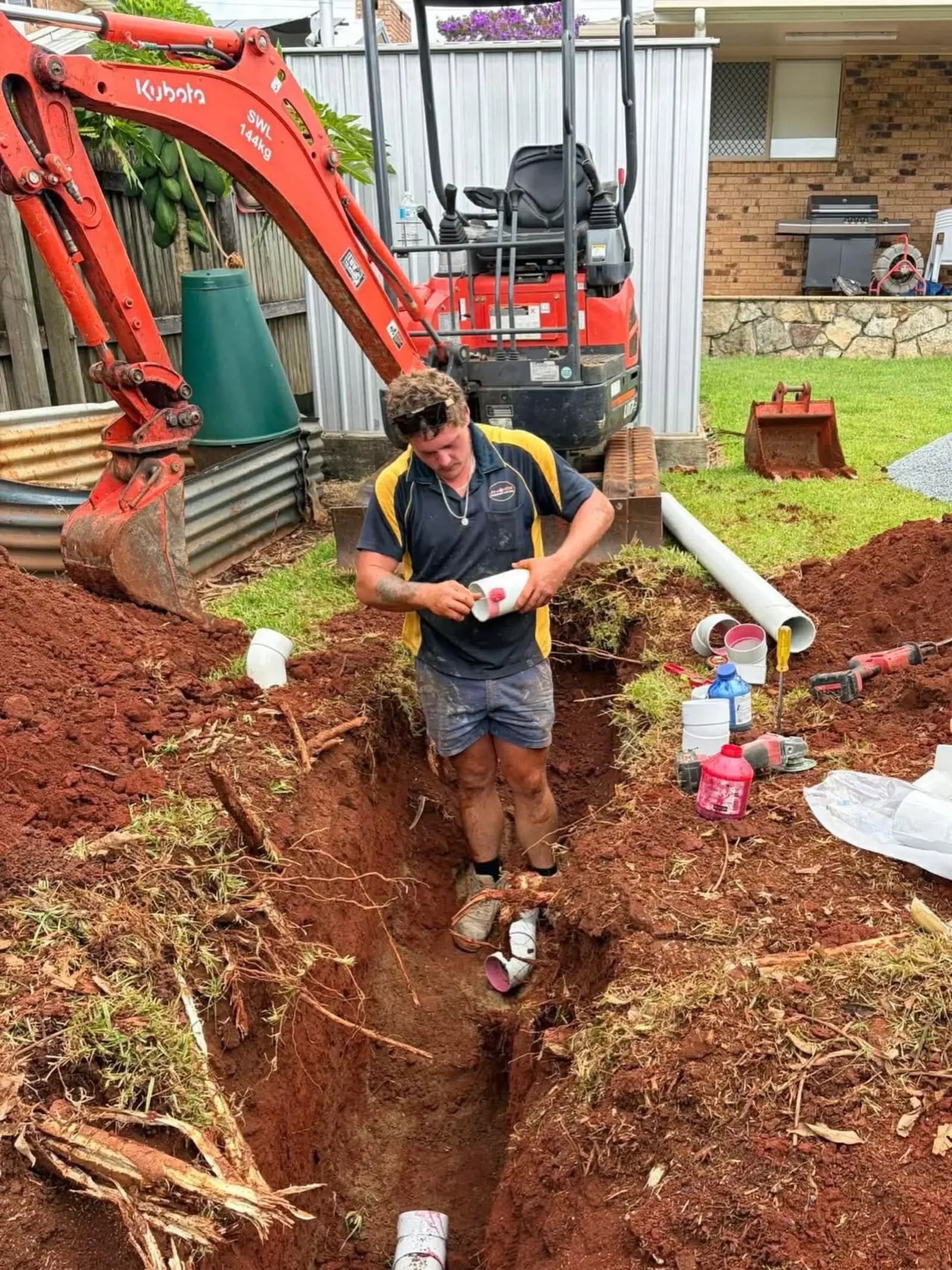 Jim Monger plumber laying pipe in a trench