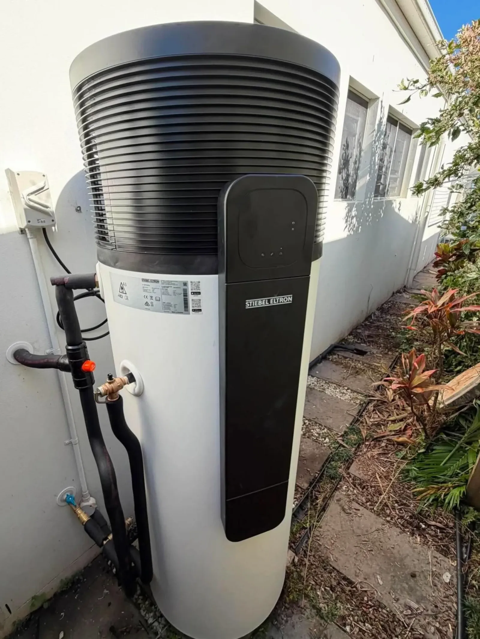 Heat pump hot water unit installed beside a house